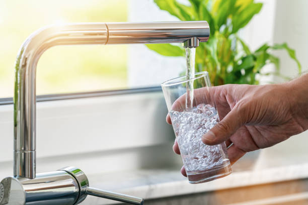 Personne qui se sert un verre d'eau au robinet