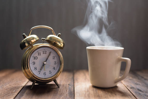 Tasse bouillante et ancien réveil sur une table en bois