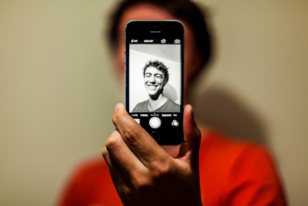 Un jeune homme preannt un selfie sur un iphone noir