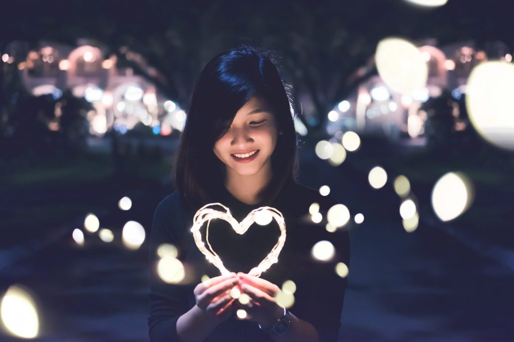Une jeune femme tenant un coeur en guirlande lumineuse dans ses mains