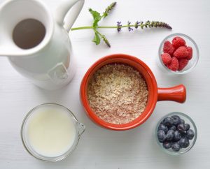 Mug rouge rempli de son d'avoine vu de haut avec fruits et lait à côté