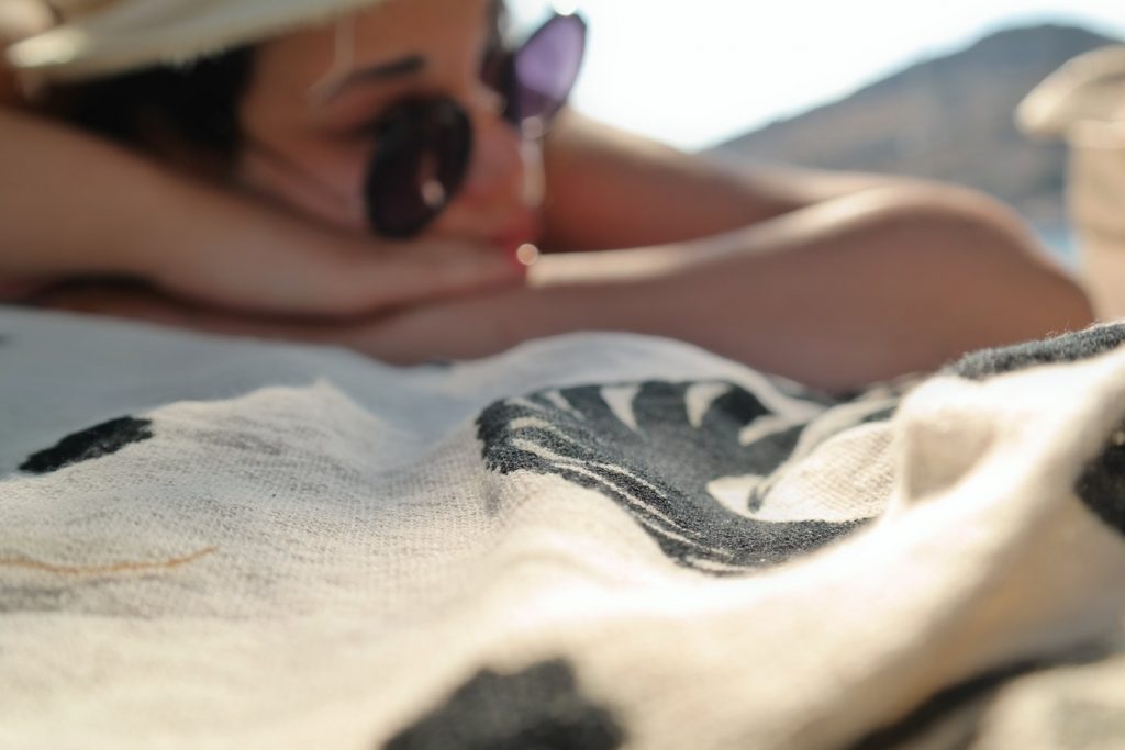 Jeune femme qui bronze sur sa serviette de plage