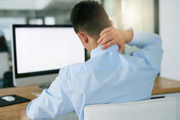 Jeune homme au travail avec douleur aux cervicales à cause de sa position assise au bureau