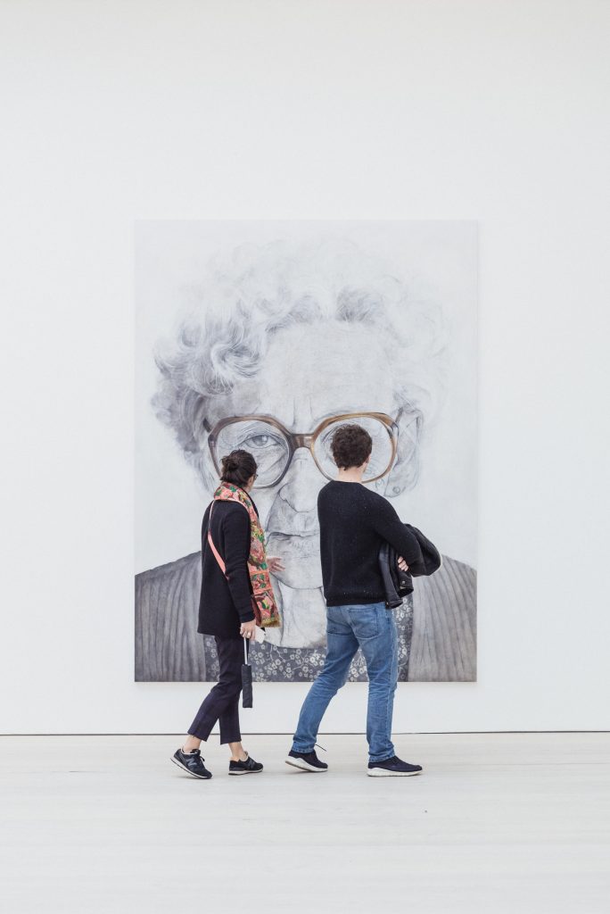 Un couple qui marche devant un grand tableau, dans un musée