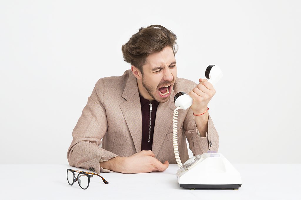 Homme qui crie dans un téléphone fixe