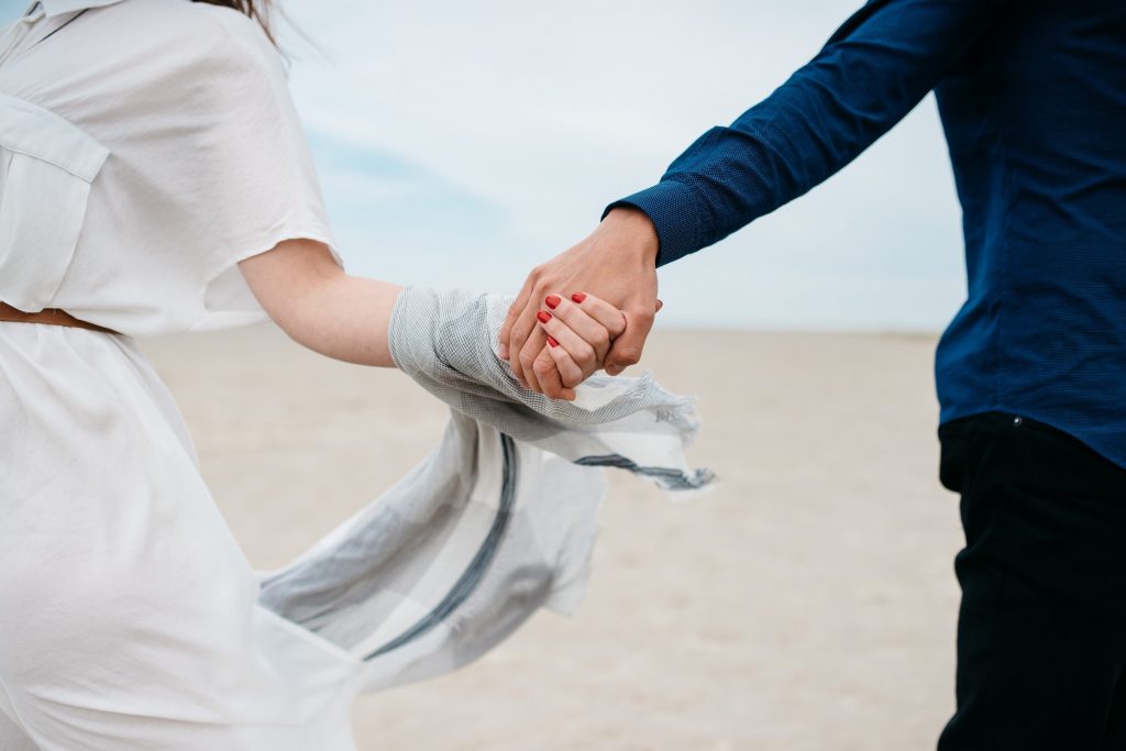 Un couple qui se tient la main en marchant sur la plage