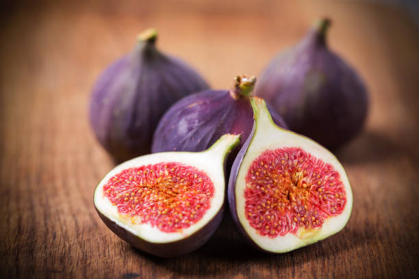 Quatre figues sur une table, dont une coupée en deux