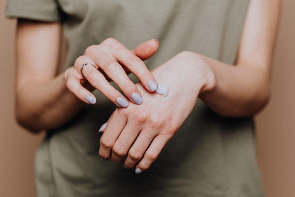 Personne qui se met de la crème sur les mains